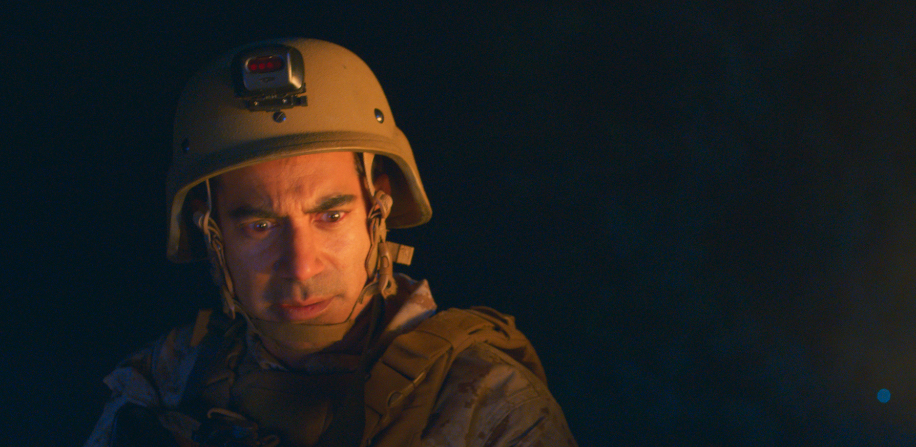 A Muslim American soldier in uniform stands in the dark.